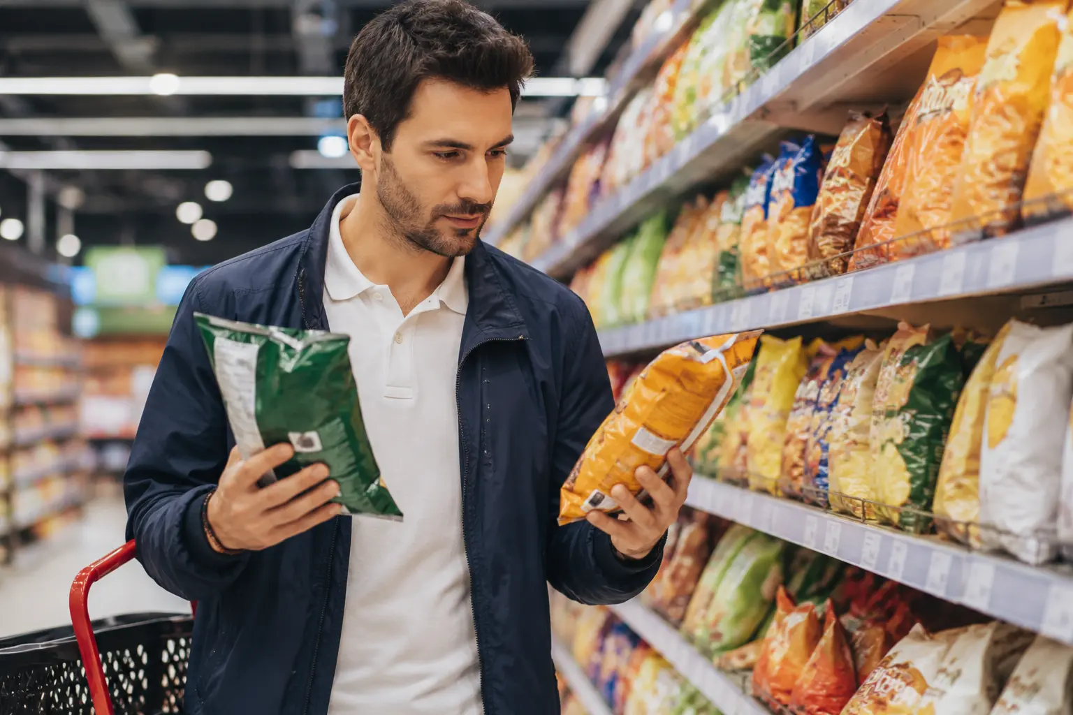 Persoană alegând chipsuri din raftul unui supermarket