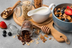Selecție de cereale pentru mic dejun, cu fulgi de ovăz, granola, cereale crocante, lapte și fructe proaspete.