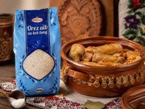 Pachet de orez alb Regal cu bob lung, 800 g, lângă o oală tradițională de lut cu sarmale.